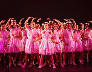 Young girls in pink ballet dresses dancing on stage