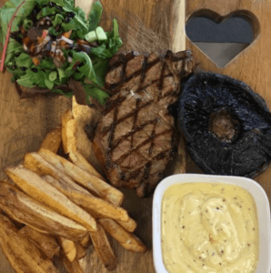 Plate of steak and chips with greens and sauce