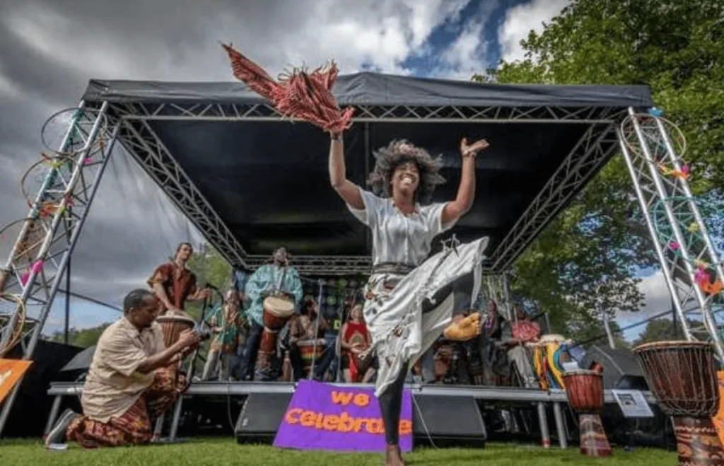 A group of diverse people dancing outside at a community event organized by Rotherham Roar Projects.